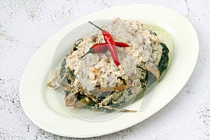 Freshly cooked Filipino dish called Spicy Pinangat Bicol or dried fish, pork, shrimp paste and gabi leaves