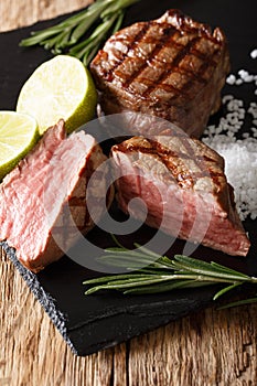 Freshly cooked mignon fillet steak with lime and rosemary close-up. vertical