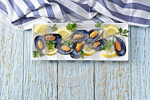 freshly cooked mussels with lemon and parsley on a white table, copy space for text