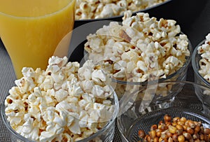 Freshly cooked popcorn in bowl and a glass of juice