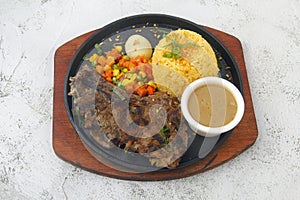 Freshly cooked pork steak served with fried rice, vegetables and gravy