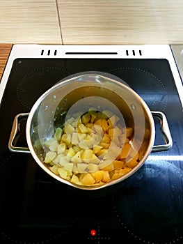 Freshly cooked potatoes in a stainless steel pot on a cooker