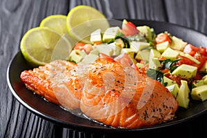 Freshly cooked salmon steak with lime, avocado and tomatoes close-up. horizontal photo