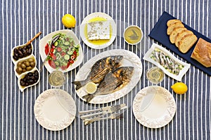 Freshly cooked seafood grilled sea bream fishes, sardines in olive oil and vegetable salad, olives, feta cheese, bread