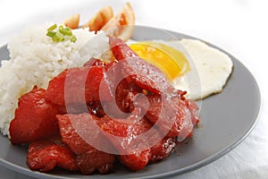 Freshly cooked Tocino or cured pork meat served with fried rice and egg with vegetables