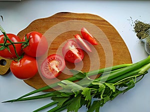 Freshly cut celery, tomatoes, green onion on wooden cutting board