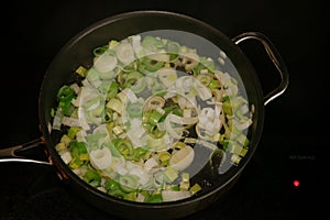 Freshly cut leeks in a frying pan on the stove ready to be cooked