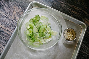 Freshly cut leeks in a glass bowl on marble surface