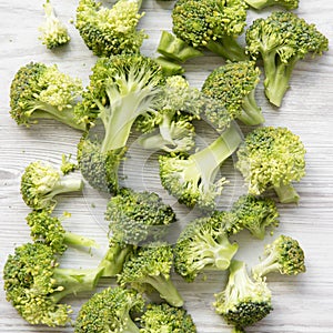 Freshly cut raw broccoli on white wooden table, top view. Flat lay