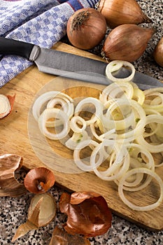 Freshly cut raw organic onion rings on a wooden board and a knife