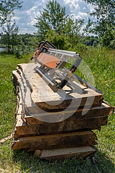Freshly cut spruce boards and chainsaws mill  placed on a pile of boards placed on a pile of boards