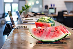 freshly cut watermelon served on an office bar with laptops around