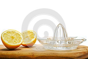 Freshly cut yellow lemon and glass juicer on a wooden board. White background