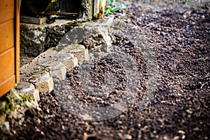 Freshly dug soil in the garden, behind it a garden shed