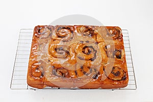 Freshly glased chelsea buns on a wire cooling rack - viewed from