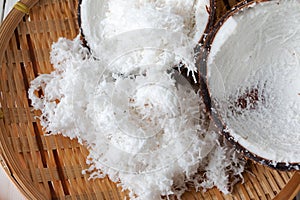 Freshly grated coconut and coconut shell on bamboo tray