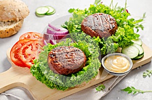 Freshly Grilled Burger Patties,Plant Based Meatless Burgers with Fresh Vegetables on a Wooden Board on Bright Background