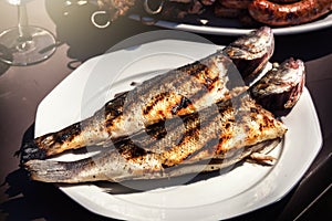Freshly grilled fishes on plate for summer outdoor party. Food b
