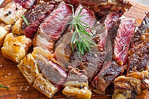 Sliced grilled vaca rubia gallega steak on wooden board with seasonings photo