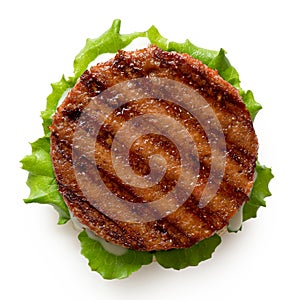 Freshly grilled plant based burger patty on bun with lettuce and sauce isolated on white. Top view