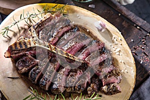 Freshly grilled T bone steak with vegetables on wooden cuting board.