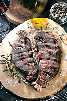 Freshly grilled T bone steak with vegetables on wooden cuting board.