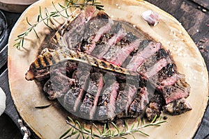 Freshly grilled T bone steak with vegetables on wooden cuting board.