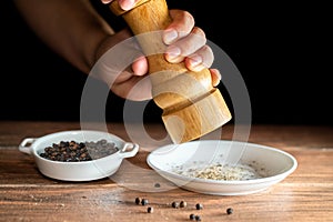 Freshly ground black peppercorns and whole black peppercorns in a white ceramic plate