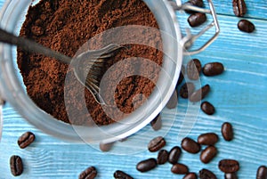 Freshly ground coffee in a glass jar, old metal spoon and scattered around coffee beans