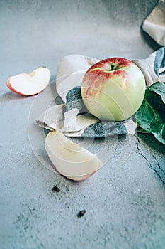 Freshly harvested ripe green red organic apples over napkin or towel and knife on table.