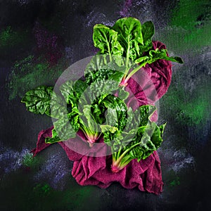 Freshly harvested spinach on dark kitchen plate and napkin