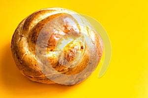 Freshly home baked artisan Easter sweet bread bun on bright yellow background. Coffee pastry. Holiday baking breakfast morning