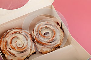 Freshly homemade Cinnamon rolls or Cinnamon buns in disposable paper box, close-up. Traditional sweet dessert buns