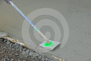 On a freshly installed cement floor, an employee of a construction company uses a stainless steel edger to form corners