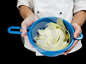 Freshly made boiled parted cabbage in a colander, held by chef i