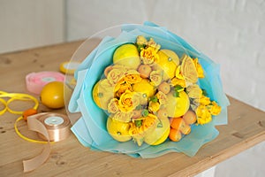 Freshly made bouquet of fruit and flowers. Yellow bouquet in blue wrapper