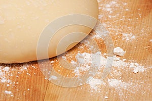 Freshly made pizza dough on a wooden chopping board