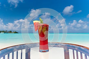 Freshly made watermelon juice with mint on the glass table ocean background at the beach