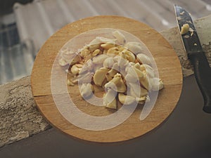 Freshly Peeled and Smashed Garlic on Wooden Cutting Board with Knife
