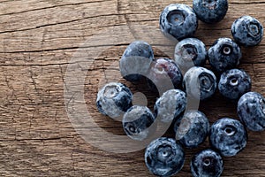 Freshly picked blueberries in wooden background. Juicy and fresh blueberries with green leaves on rustic table.