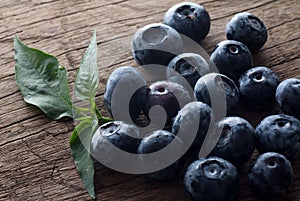 Freshly picked blueberries in wooden background. Juicy and fresh blueberries with green leaves on rustic table.