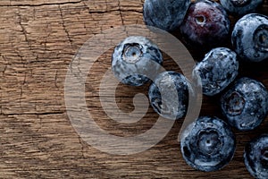 Freshly picked blueberries in wooden background. Juicy and fresh blueberries with green leaves on rustic table.