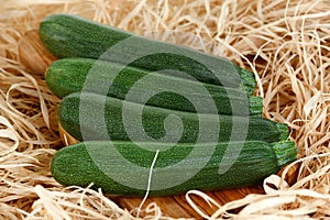 Freshly picked Green zucchin on cutting board and straw. background, texture