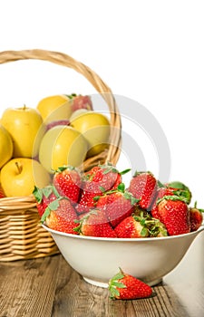 freshly picked organic strawberry and apples in a basket isolated over white background, healthy eating