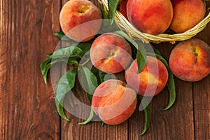 Freshly picked peaches in basket on a brown wooden background. Ripe peaches in basket on wooden table