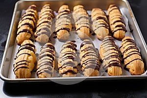 freshly piped eclair cases dry on a baking sheet