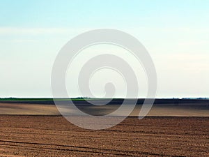 Freshly ploughed undulating hills of brown and sand color farm land with hills