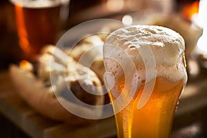 Freshly poured amber beer in mug served with bratwursts