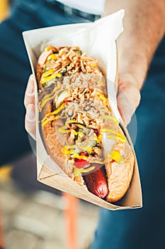 Freshly prepared hotdog with lush salsa cauce in a paper box. Food delivery or take away food concept photo