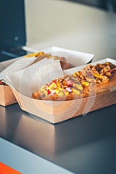 Freshly prepared hotdogs in a paper box on a showcase of food track. Food delivery or take away food concept